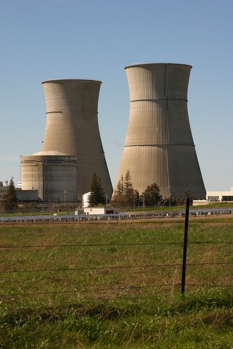 two cooling towers sitting on top of a field
