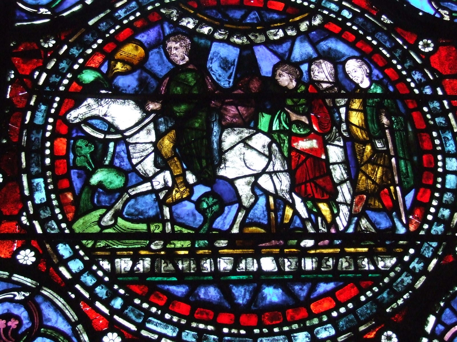 a colorful stained glass window shows people riding horses