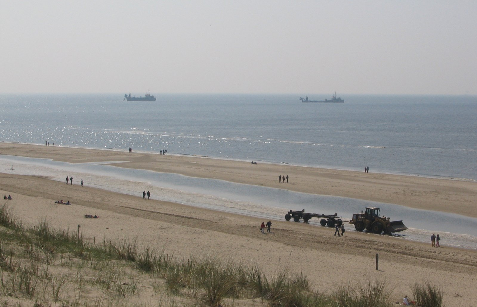 people are standing on the beach next to water