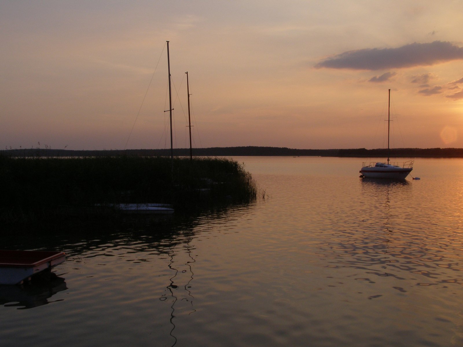 a number of small boats on a body of water at dusk