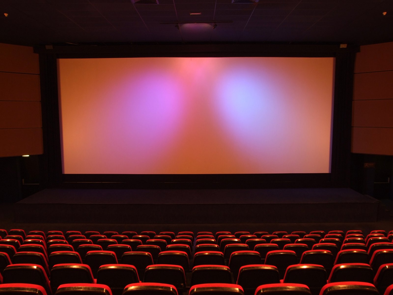 large auditorium with multiple rows and orange screen