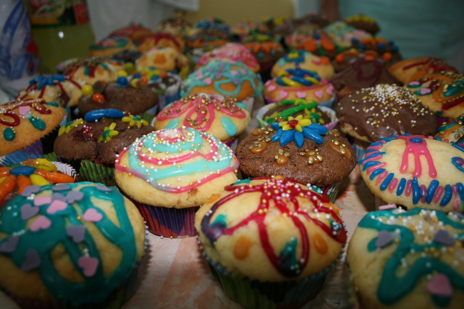 many brightly colored decorated cup cakes and muffins