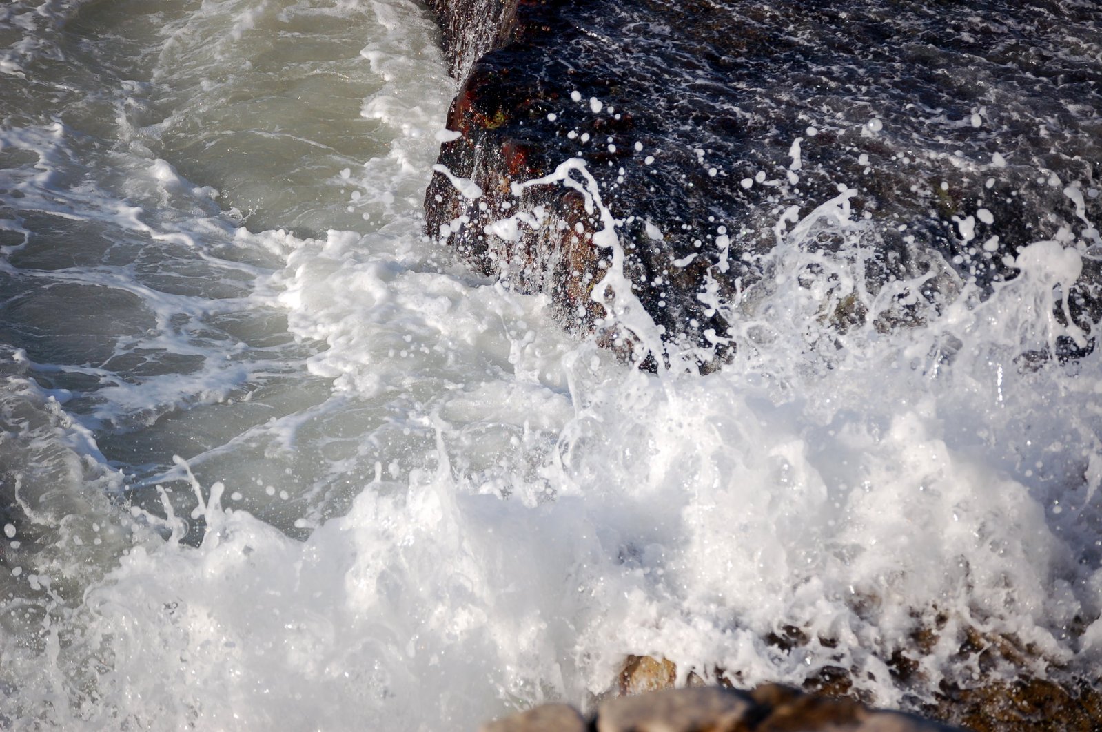 a close up view of the water on a wave hitting rocks