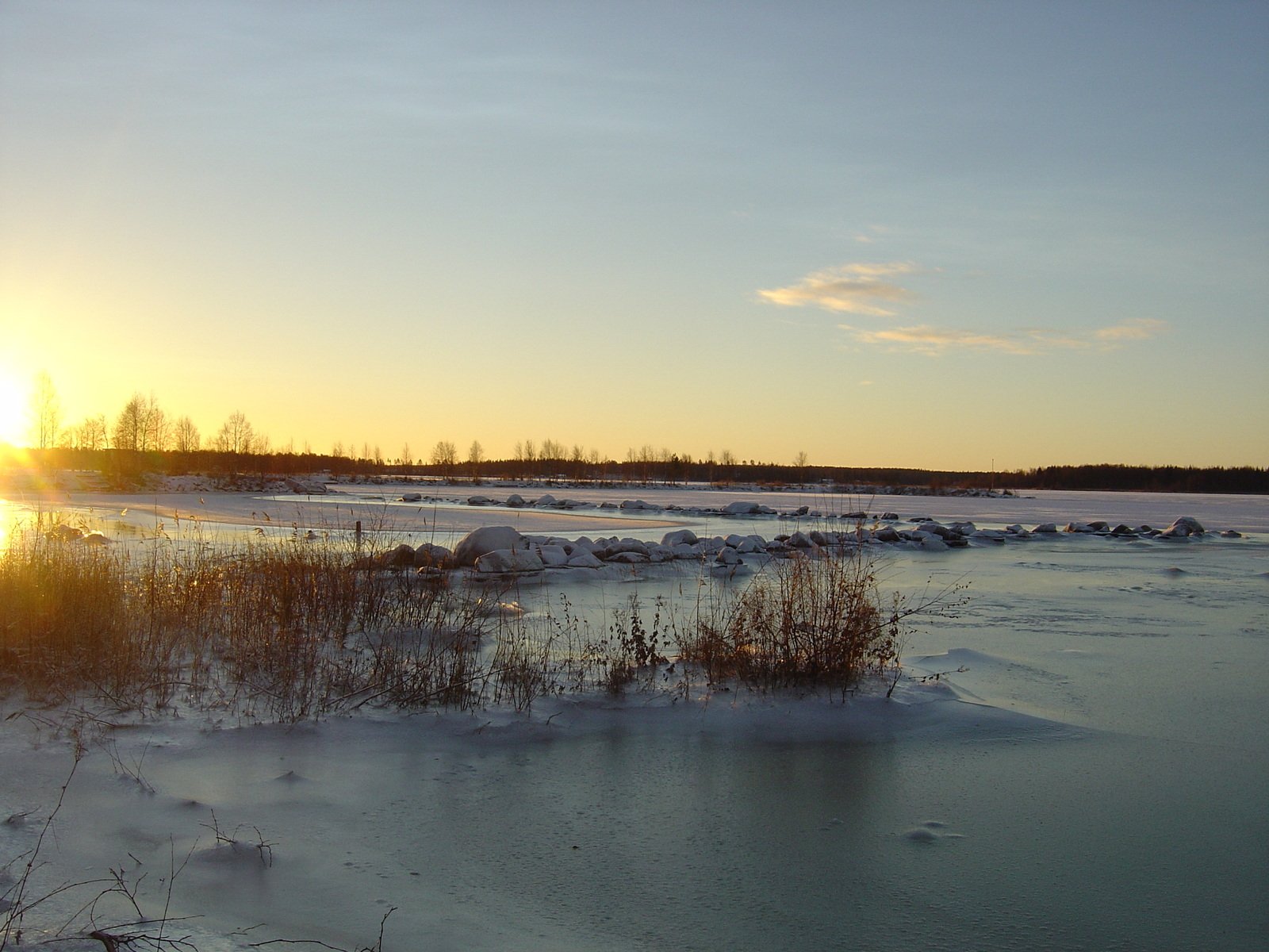 the sun is setting over an ice covered shore