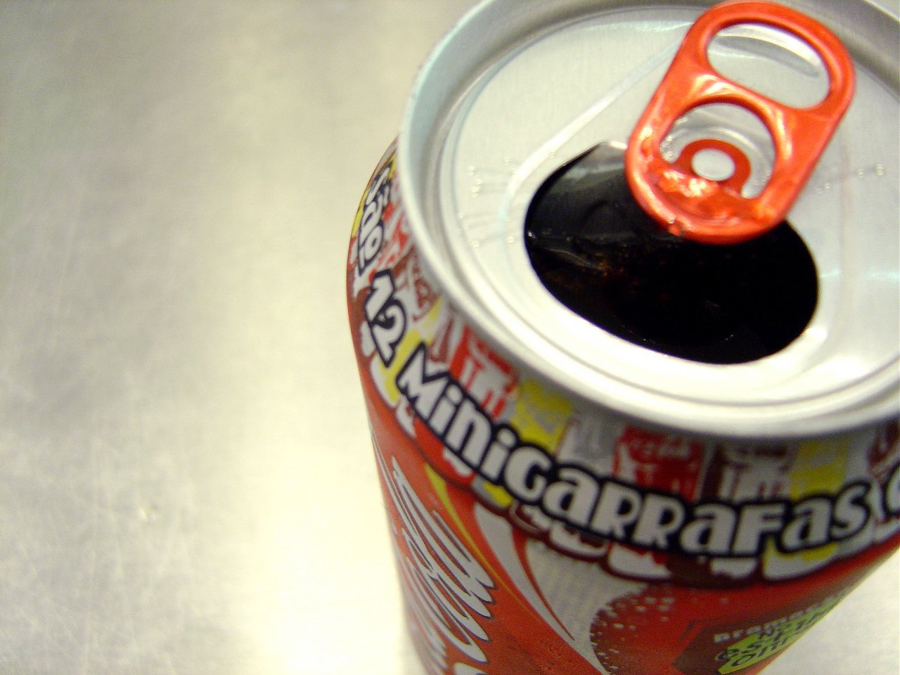 a can of soda with an orange cap and the lid