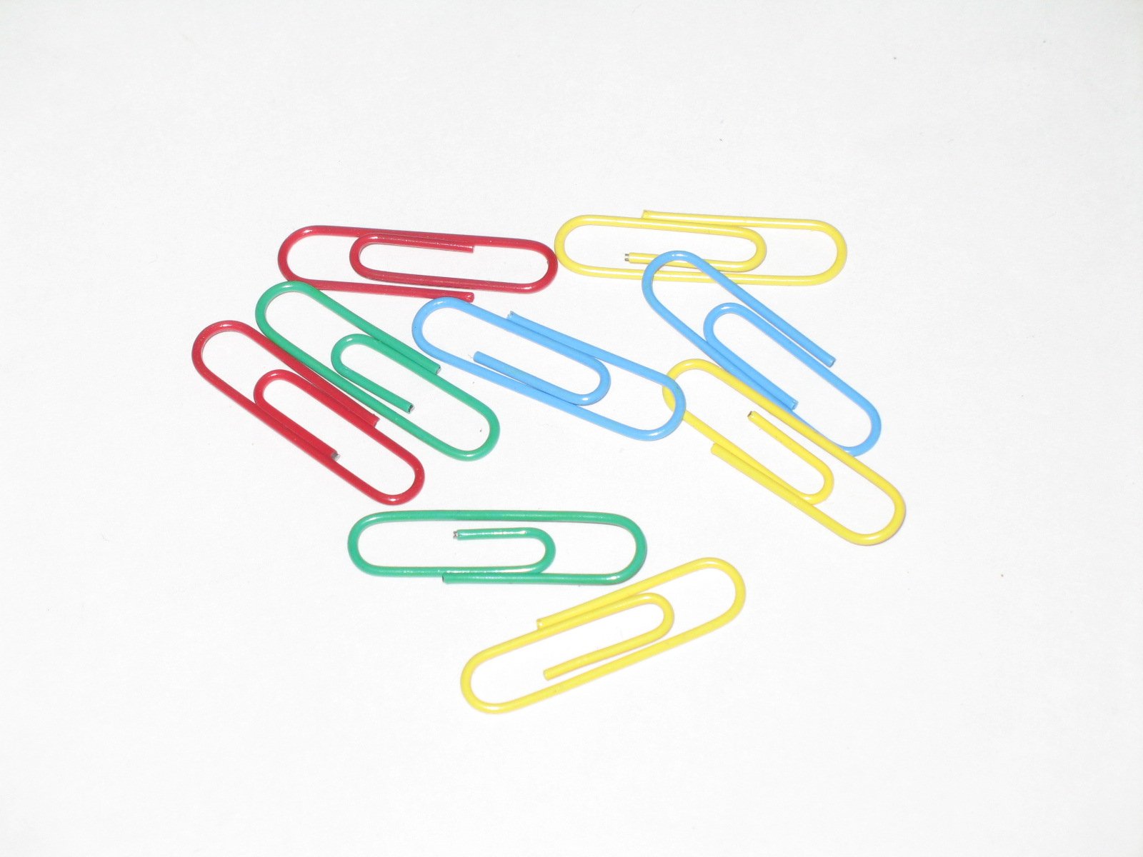 a white background has several rainbow colored paper clips with thumb tips