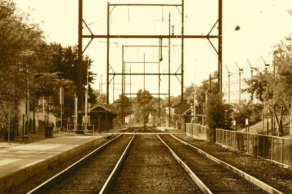 a sepia - toned po of train tracks at an old time station