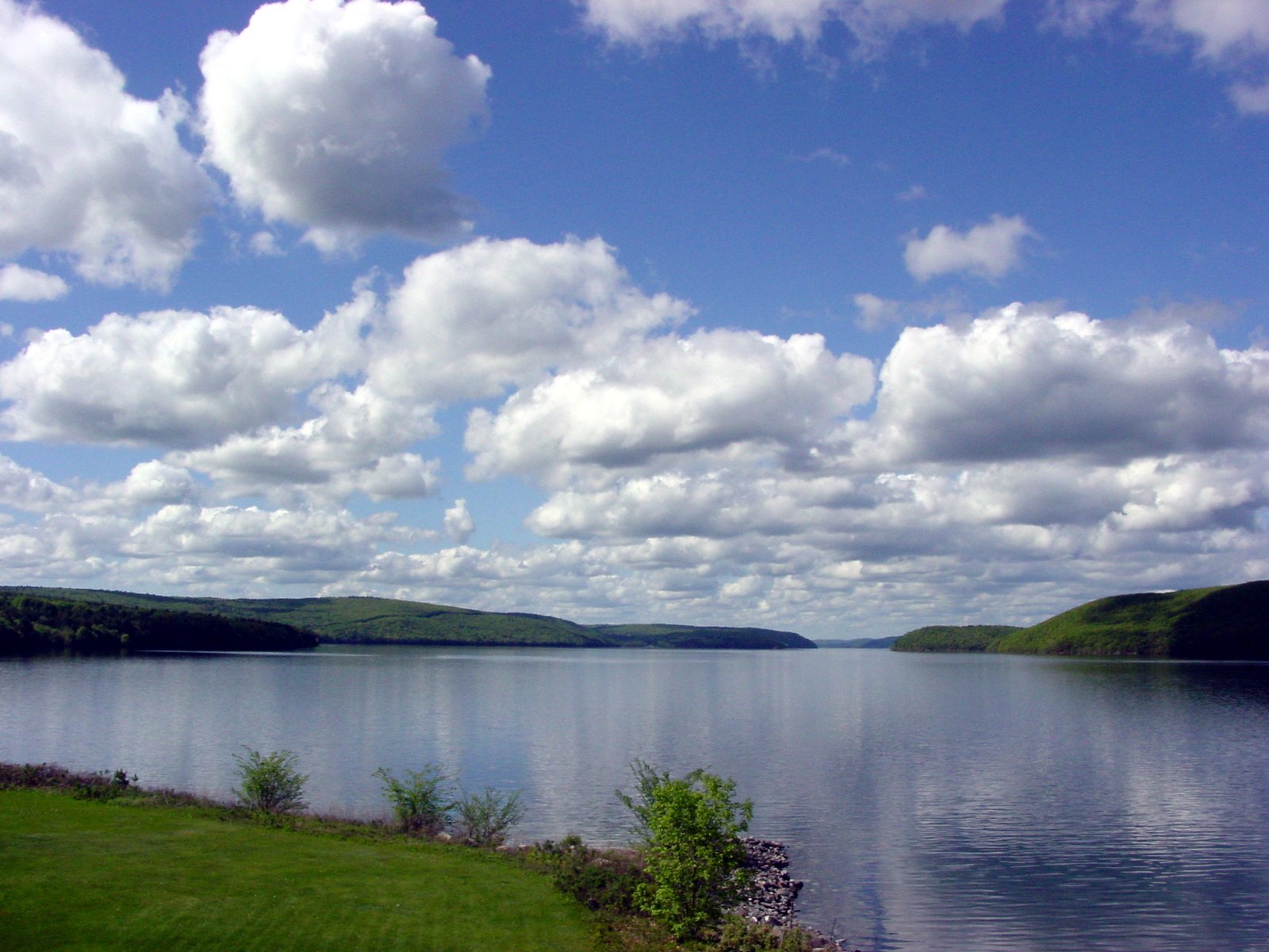 the large body of water has small hills and grass on both sides