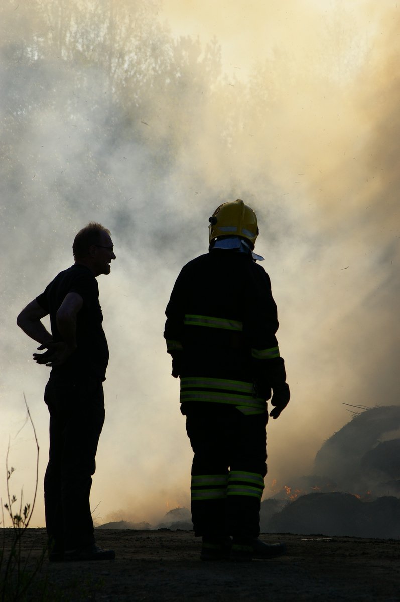 two fire fighters stand in front of a fire that was blazing