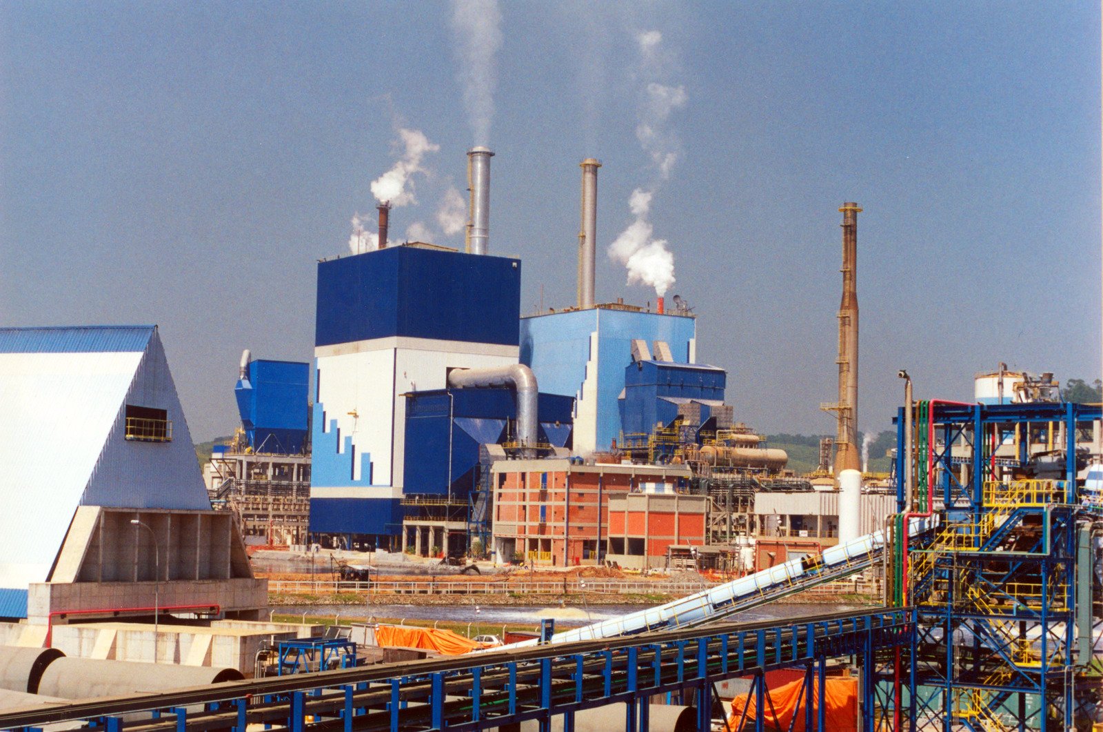 a blue and white industrial plant with smoke billows