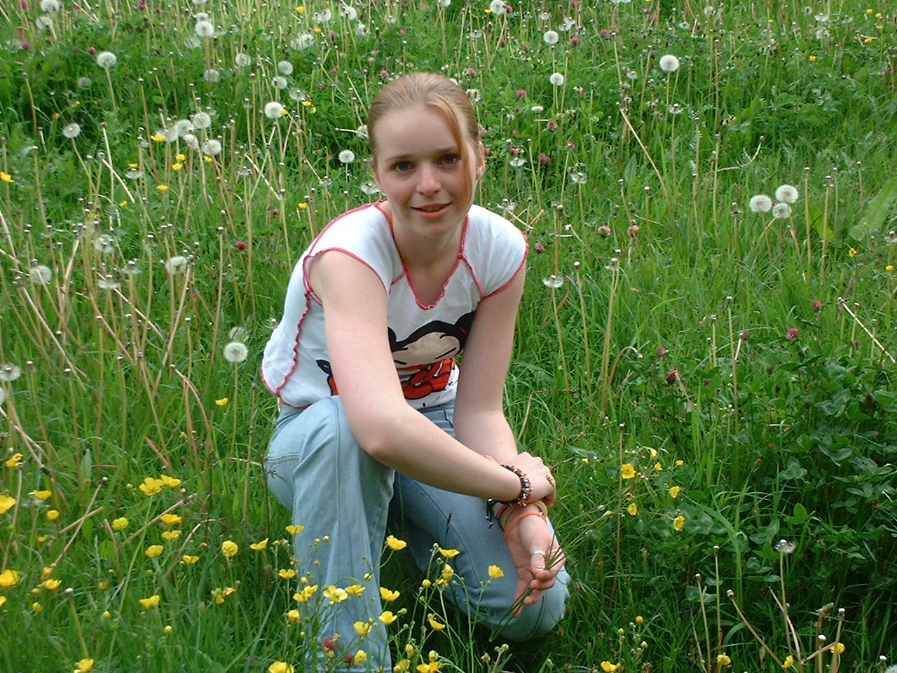 a woman kneeling in a field of flowers