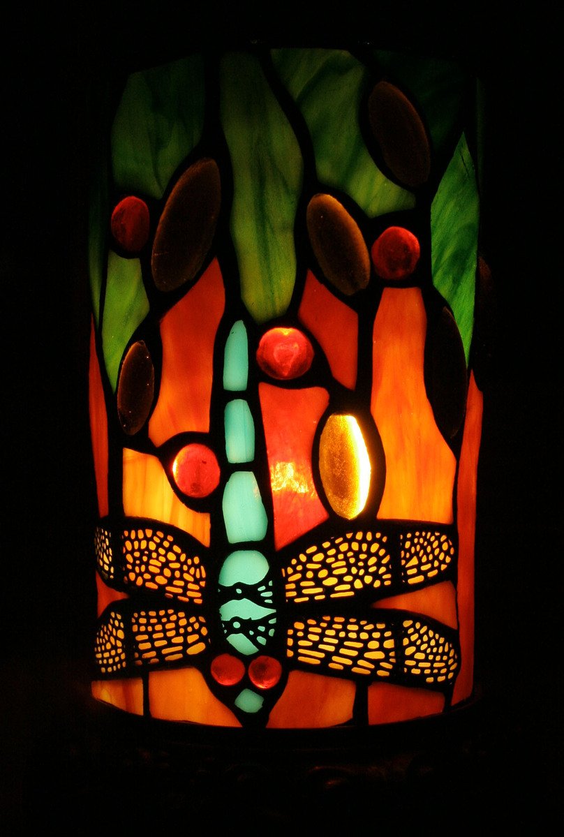 a small lit up dragonfly in stained glass