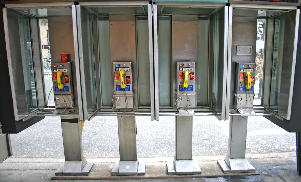 there are four telephone booths standing on a street corner