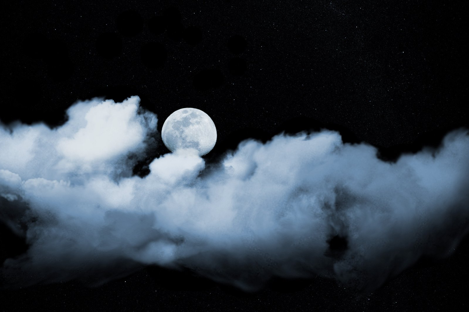 a large moon in the distance among a cloud formation