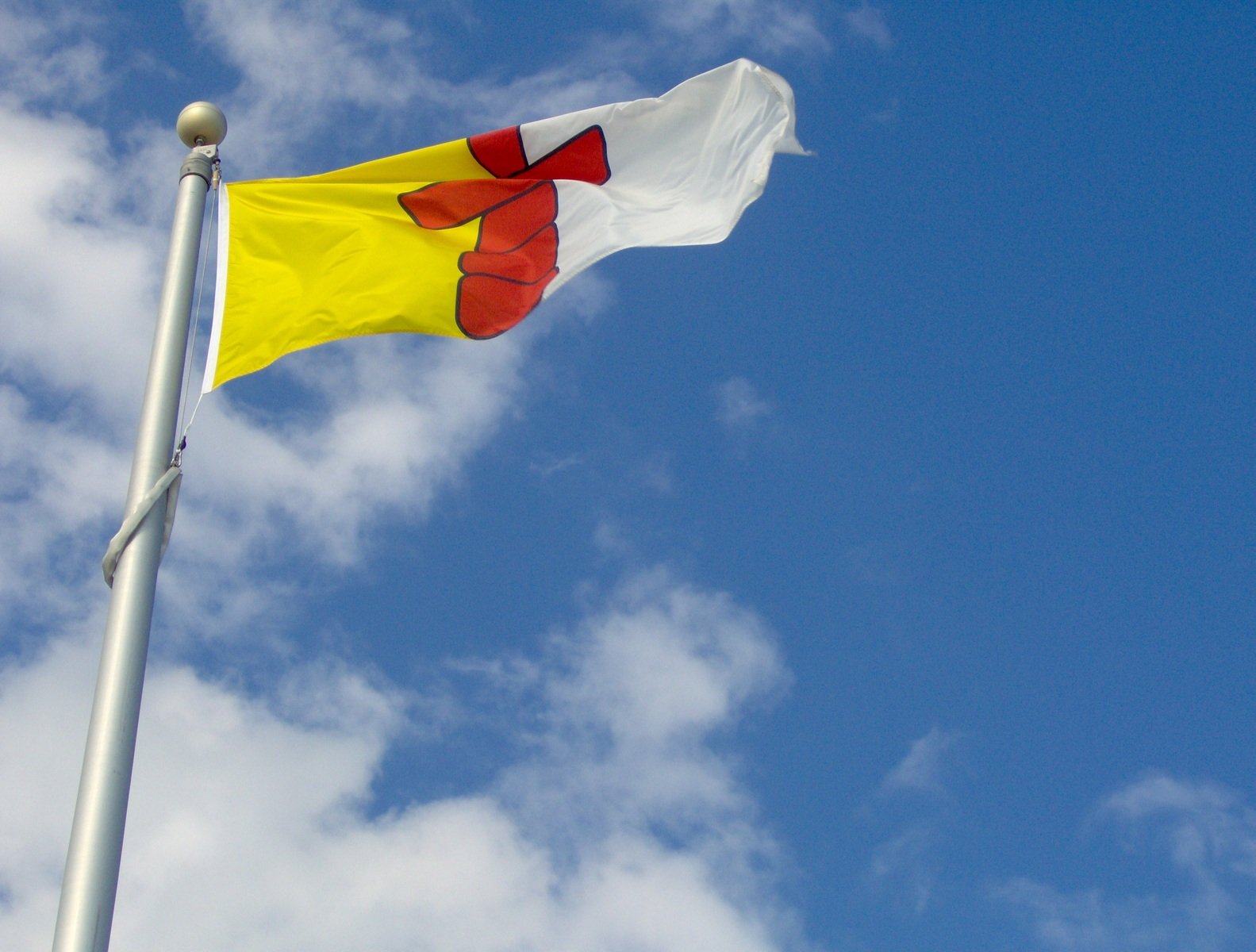 a flag pole with the top half of a yellow and red flag flying above