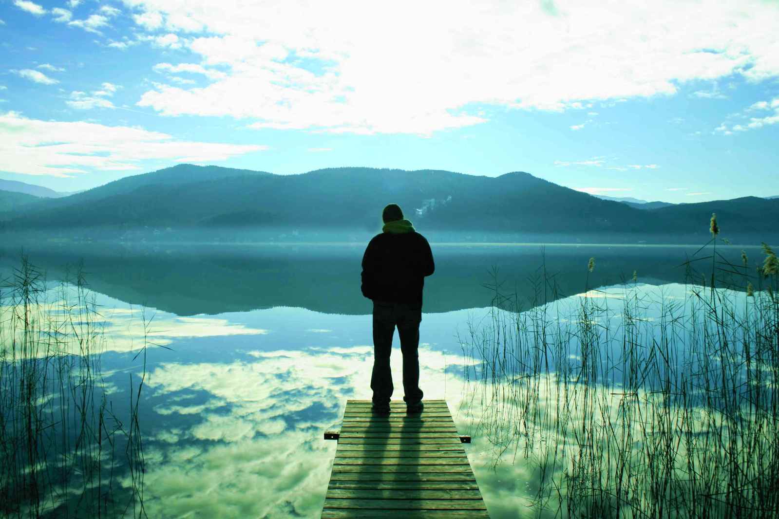 a man standing at the end of a wooden dock