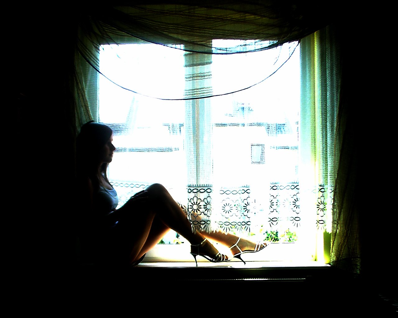 a woman sitting on a window sill looking outside