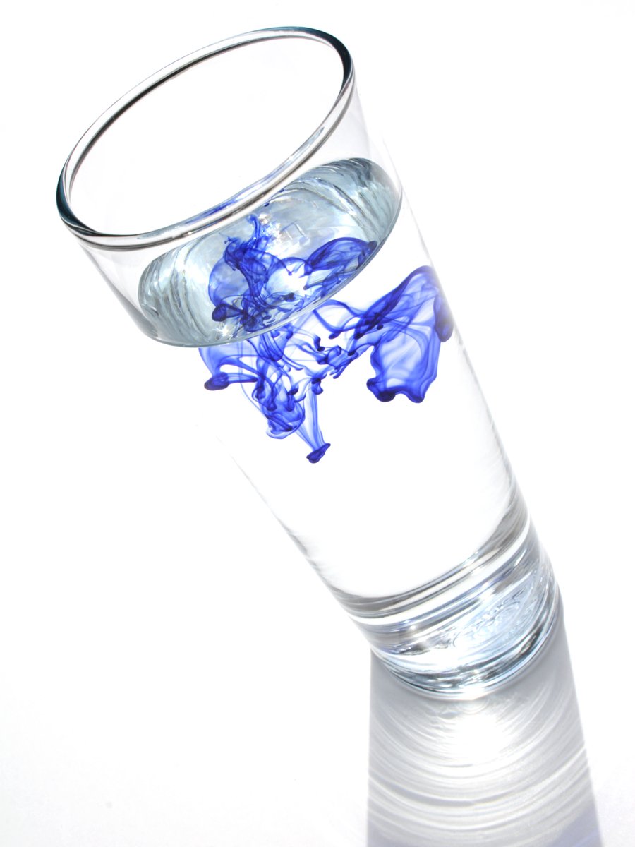 a blue and white flower in water in a glass