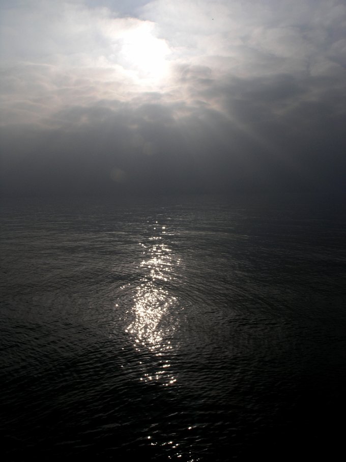 the sun shines through clouds over water