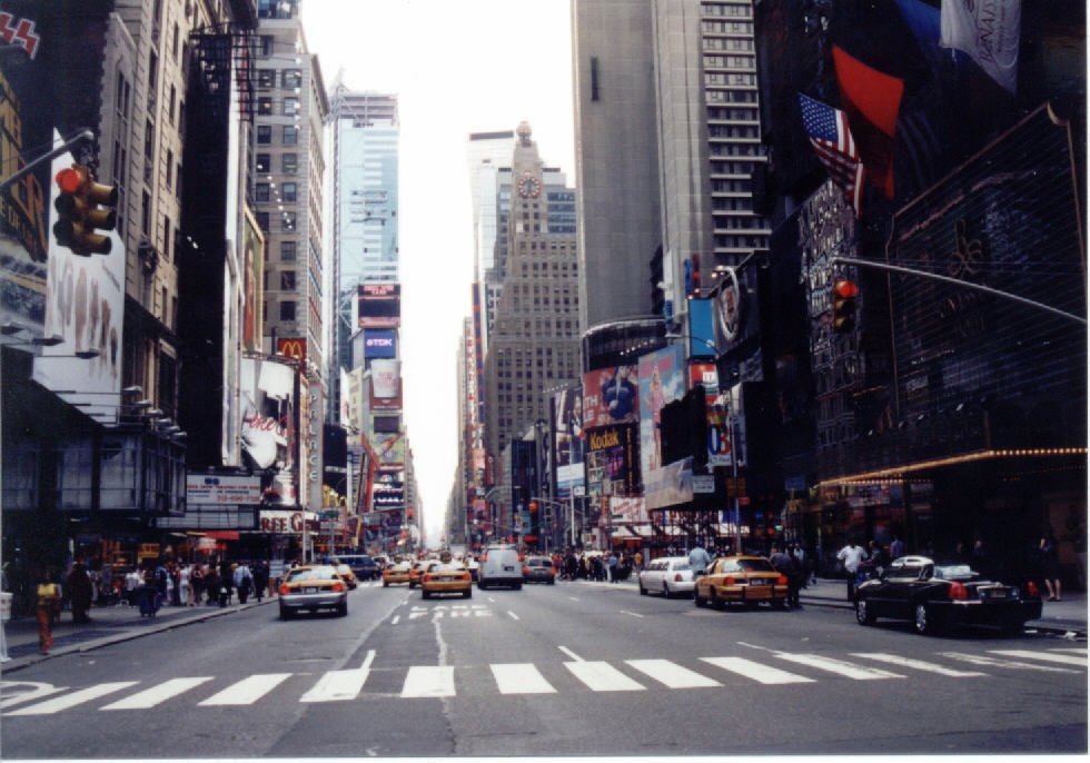 a city street with cars and people crossing the street