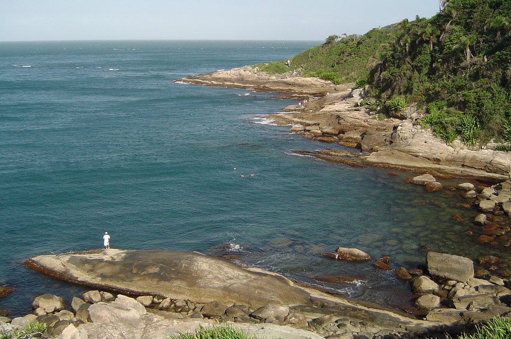 a small lighthouse is at the edge of a large body of water