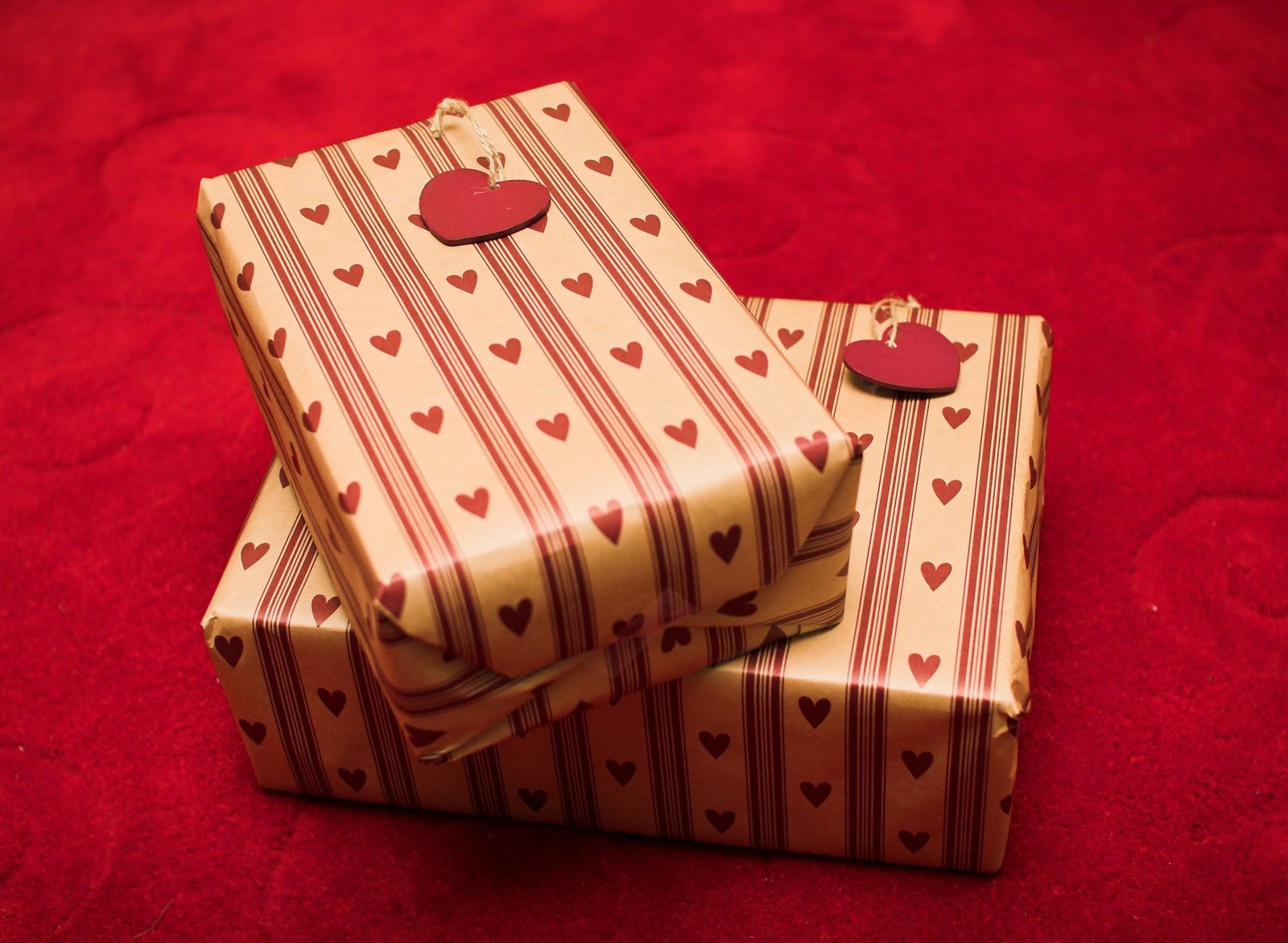two wrapped christmas gifts sit on a red cloth