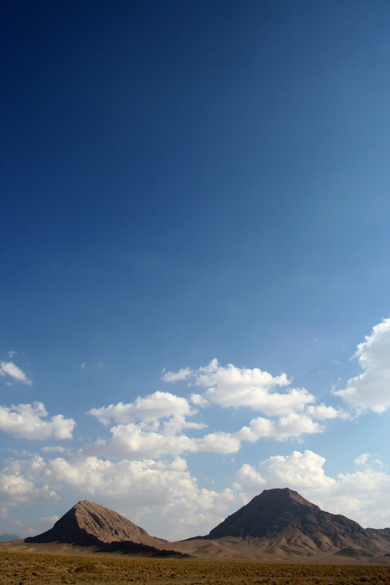 the distant mountains are under a blue sky with clouds