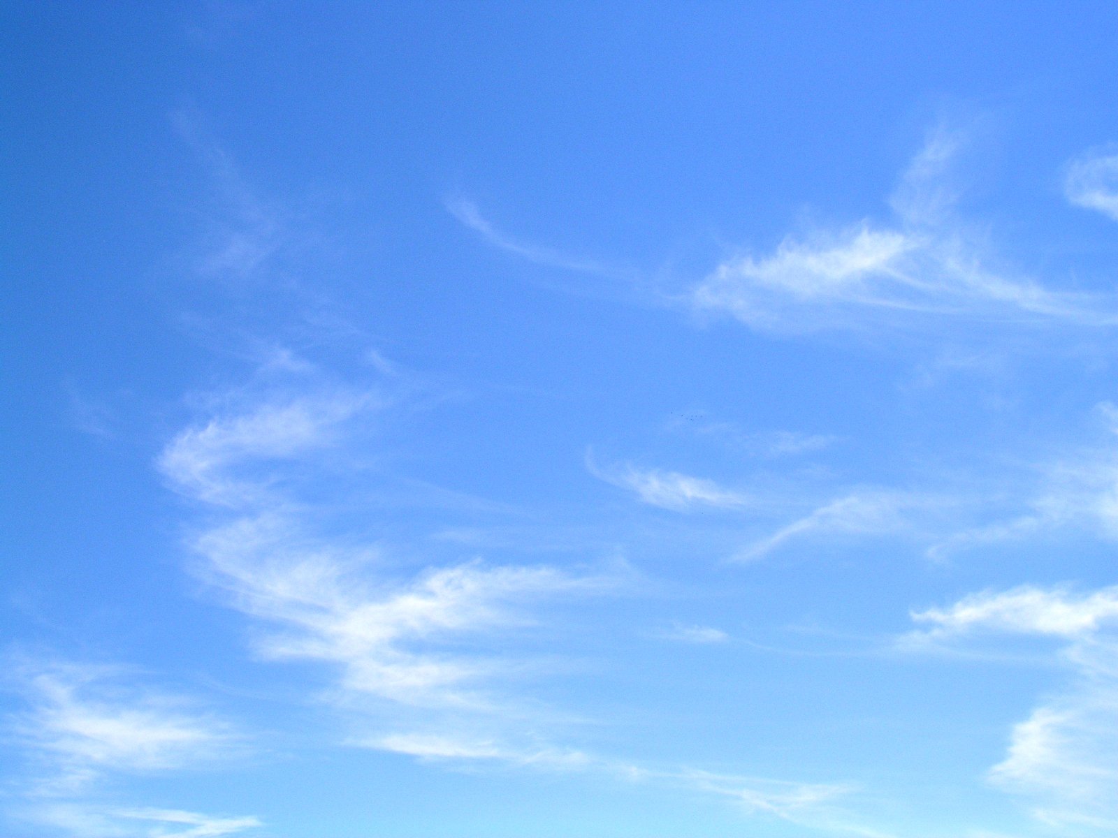 an airplane flying in a blue sky with some clouds