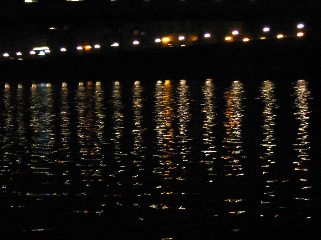 the dark water reflects lights in the night sky
