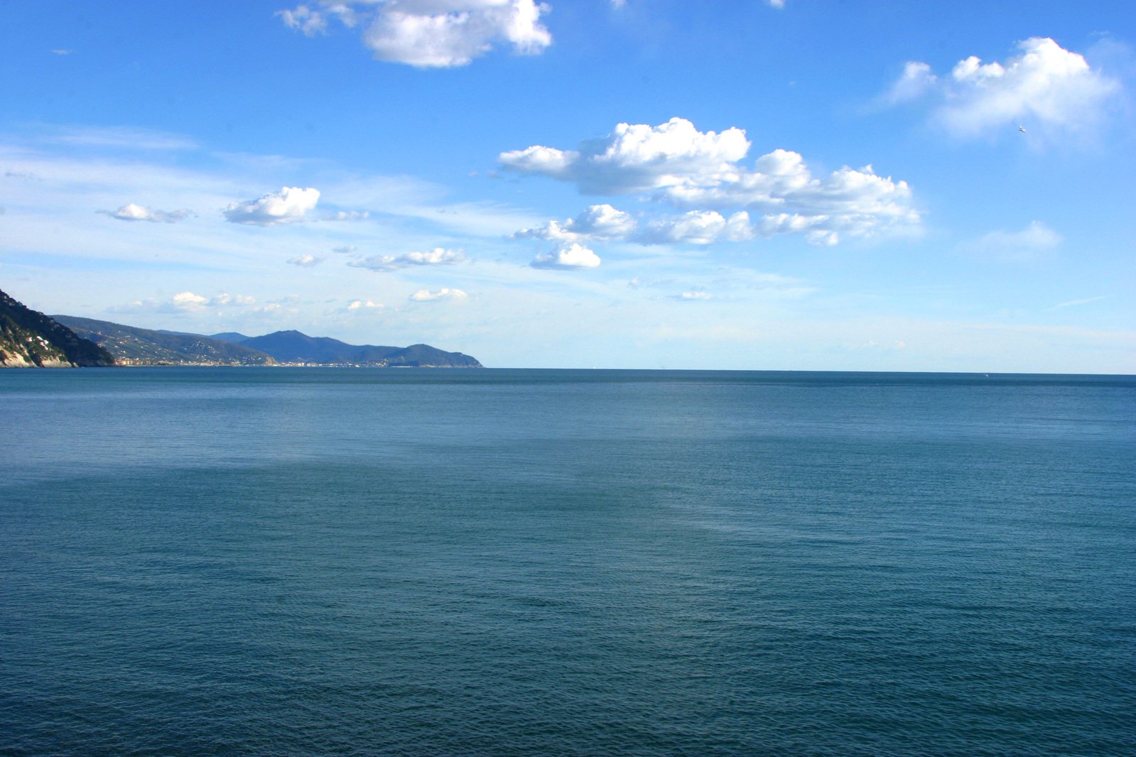 an open, crystal blue water has clouds over the mountains