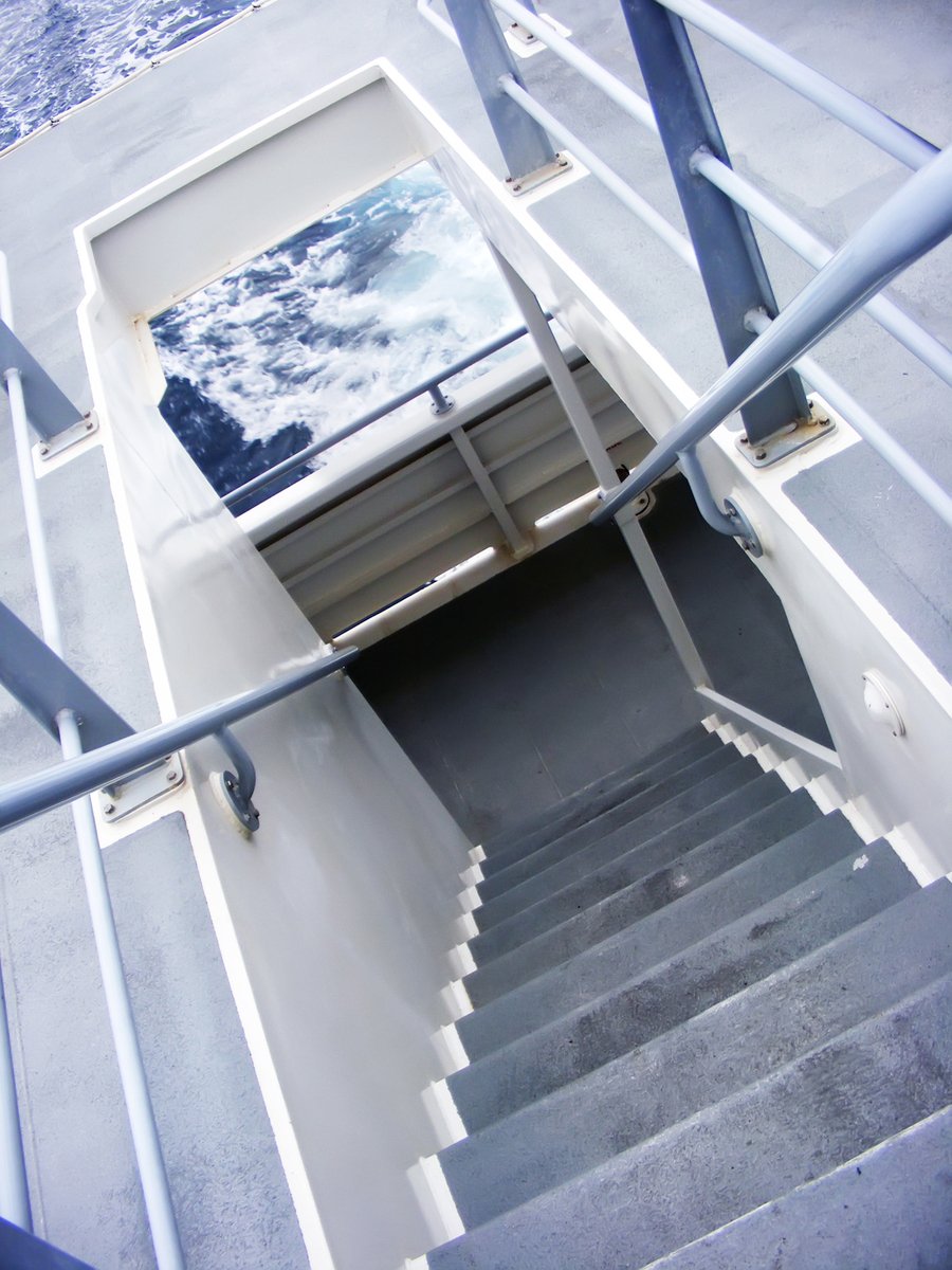a stairwell leading down to a balcony next to the ocean