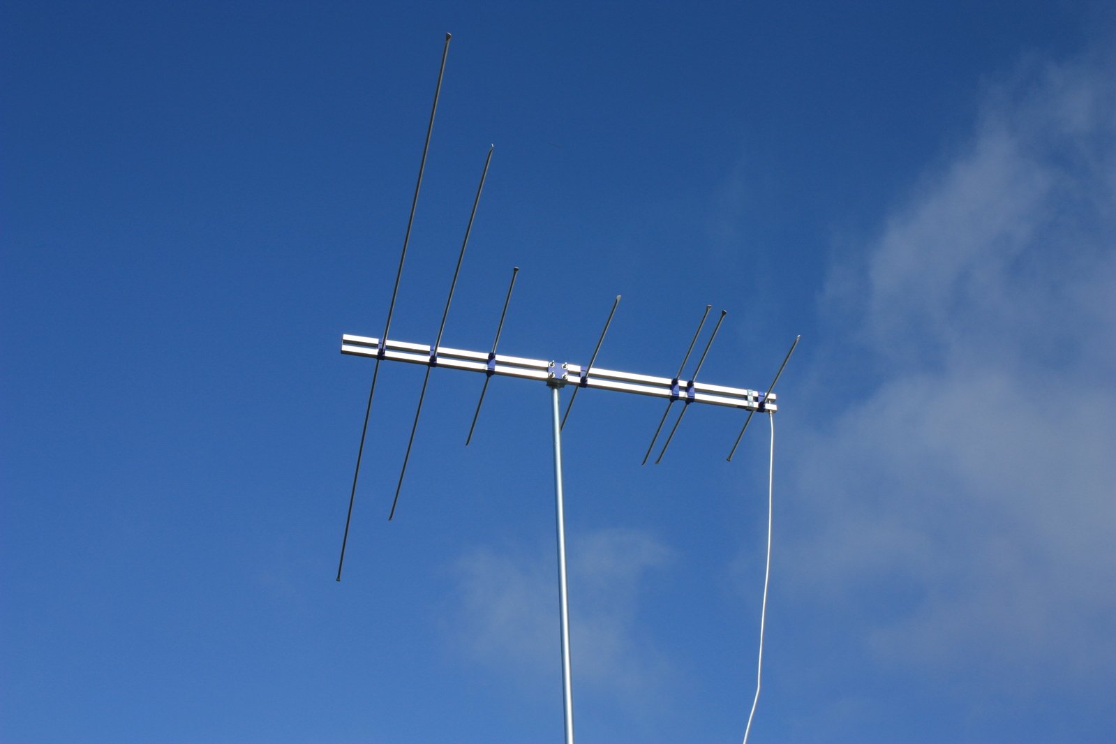 a large tv antenna sitting on top of a blue cloudy sky