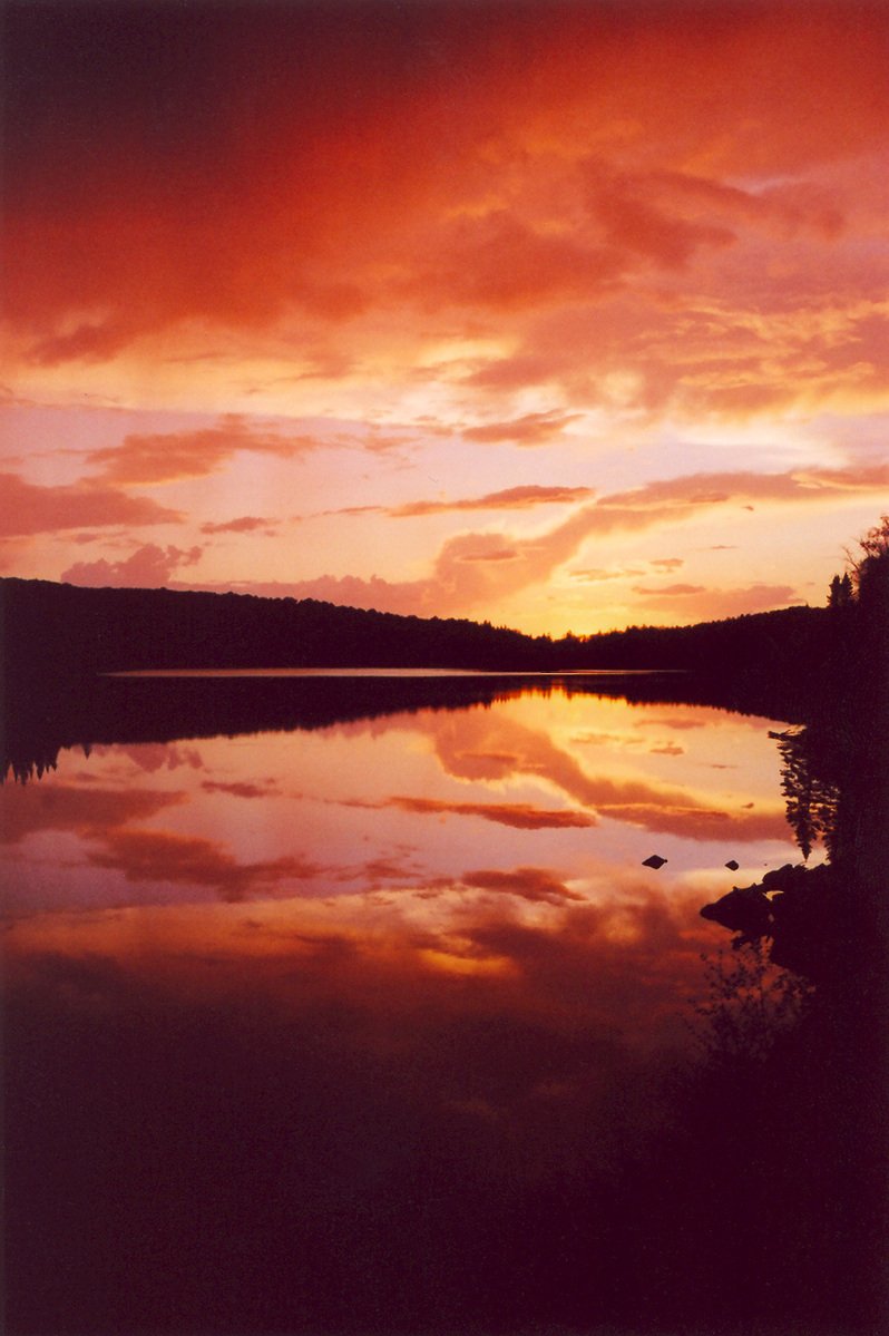 the sun is setting on the horizon with clouds