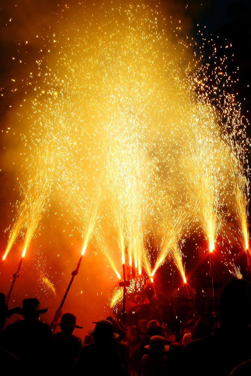 fireworks that are set off and illuminating and some people watching