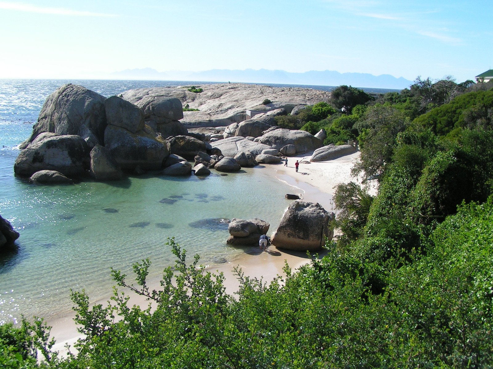 a beach with lots of rocks and people on it