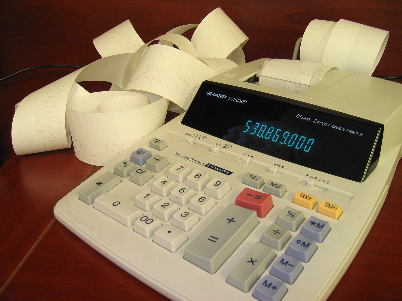 the calculator is on the table, next to tape and a roll of toilet paper