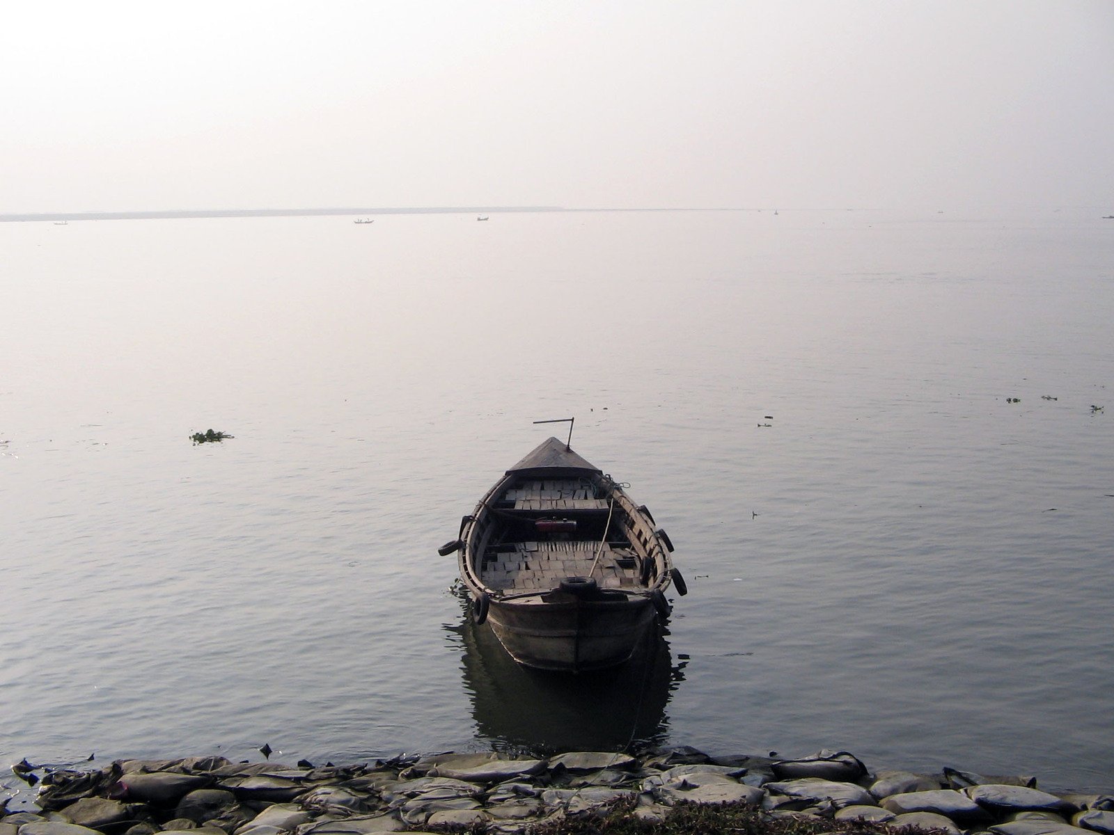 a boat sits on the shore while birds are floating in the water