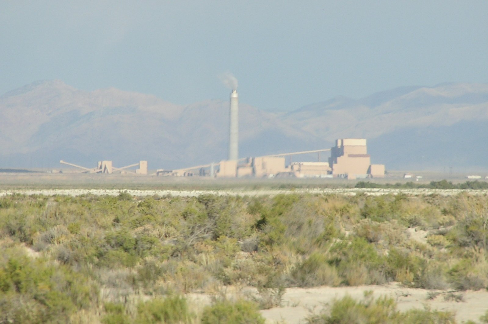 a view of an industrial plant with hills in the background