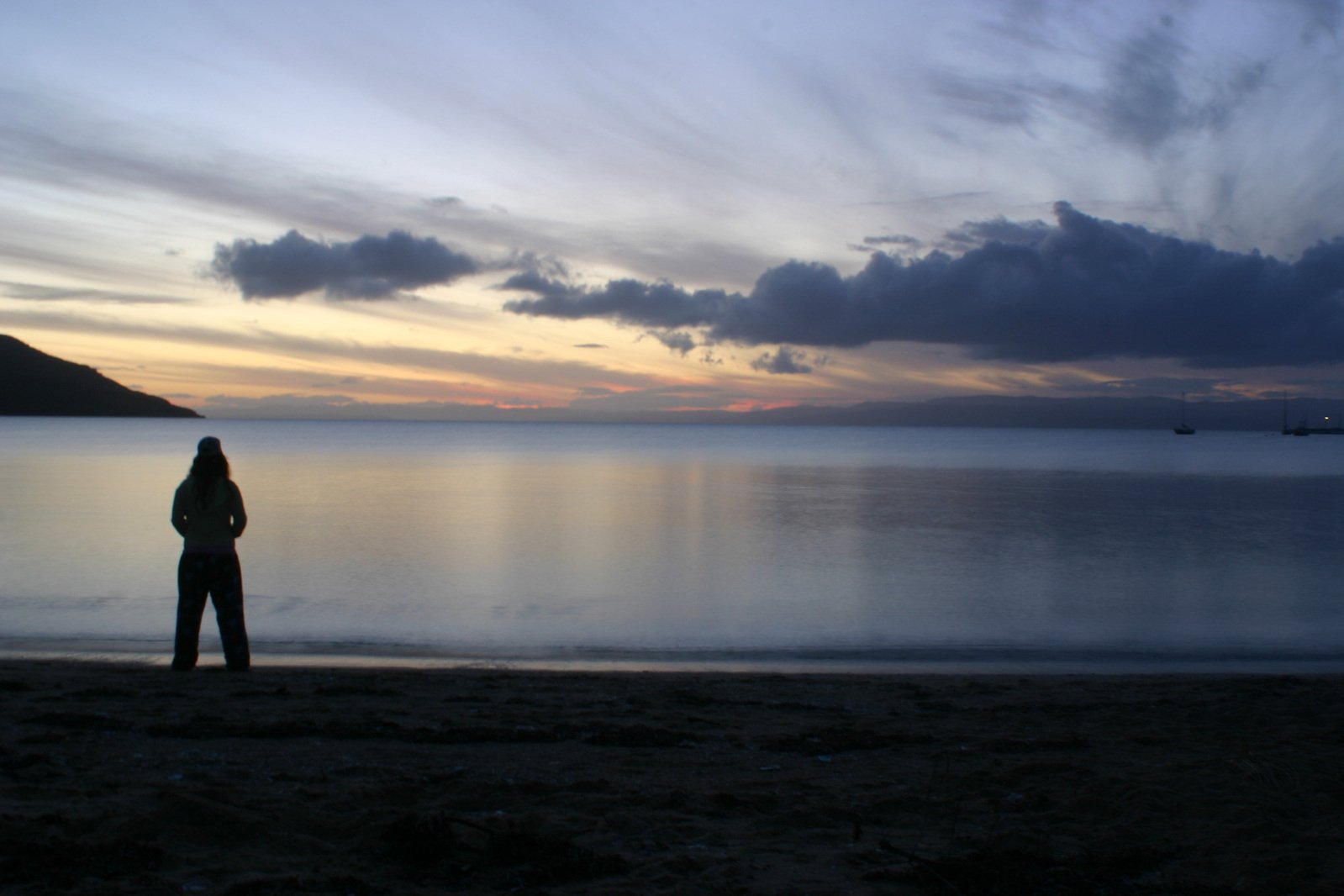 man watching sun set from beach looking at ocean