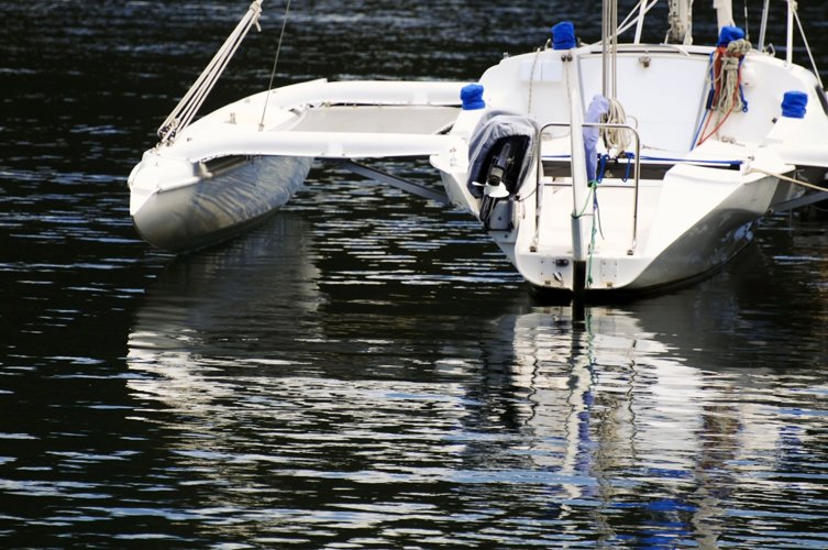 a white boat sits in the water near another boat