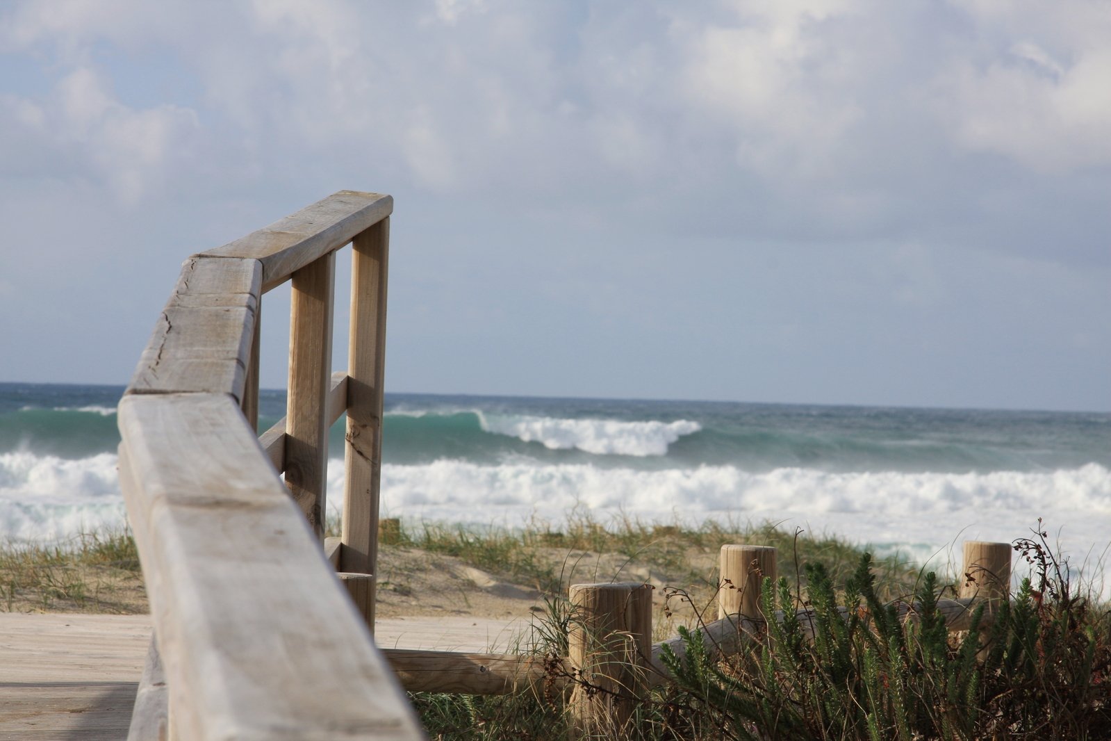 the bench overlooks the beach as an ocean approaches
