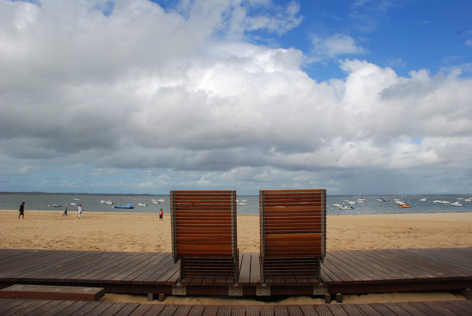two wooden benches sit next to each other on a boardwalk
