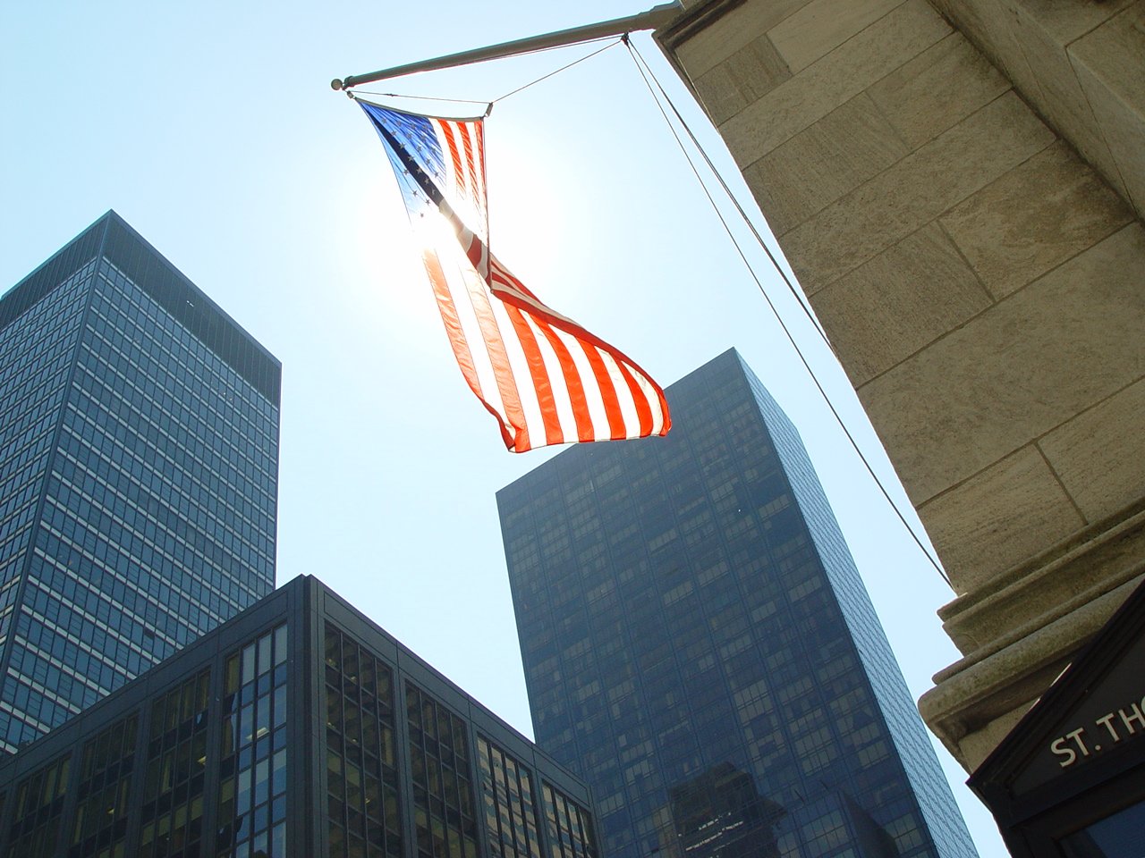 a flag flying high in the air with skyscrs behind it