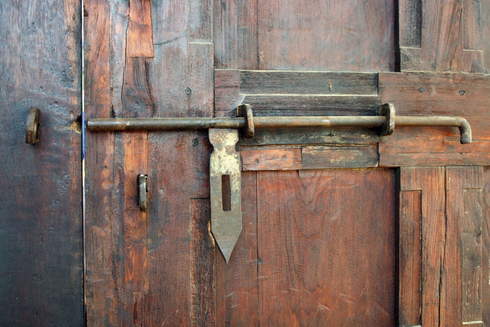 the large wooden door has a long metal bar