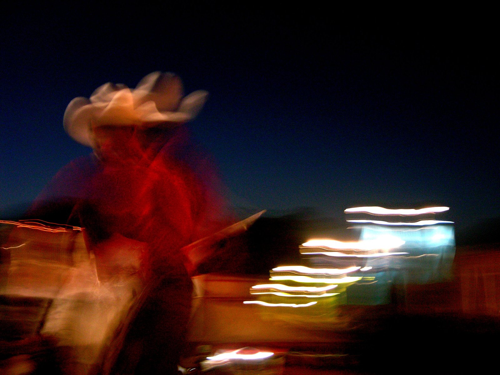 blurry image of a cowboy standing next to his horse