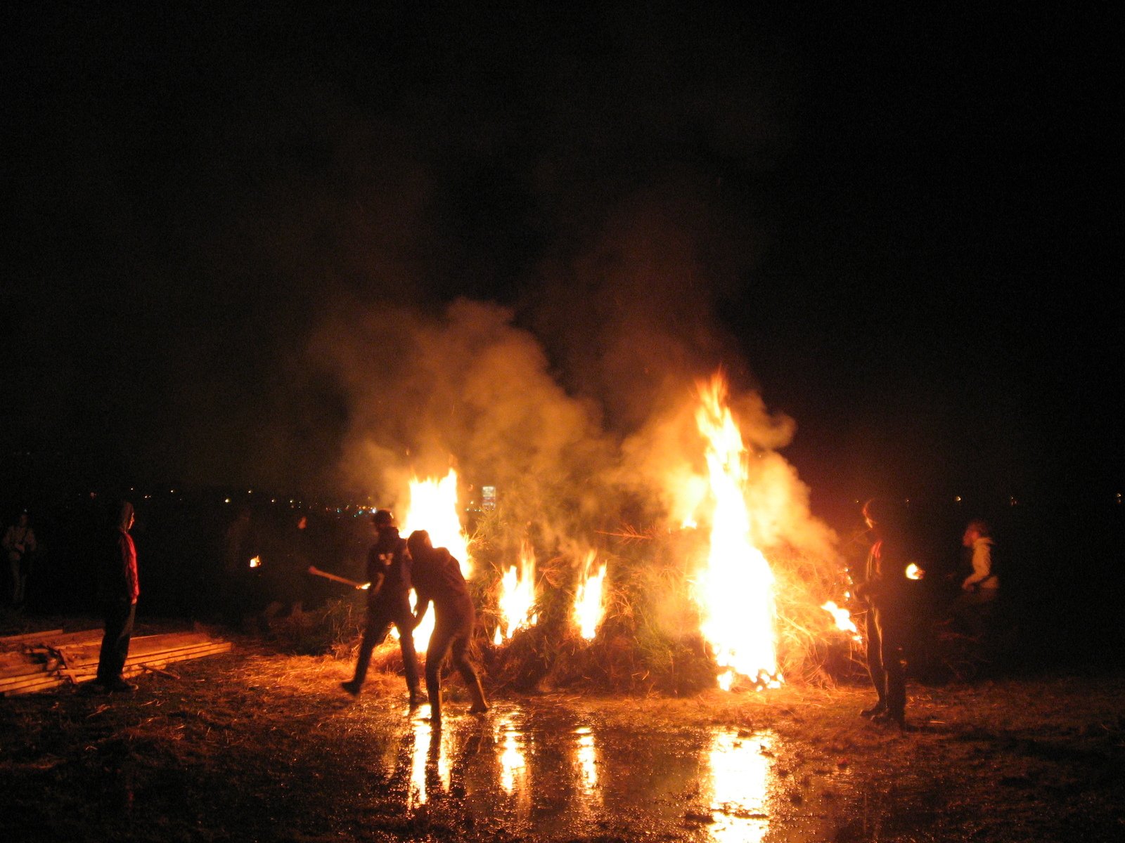 people dancing around a large fire with many flames