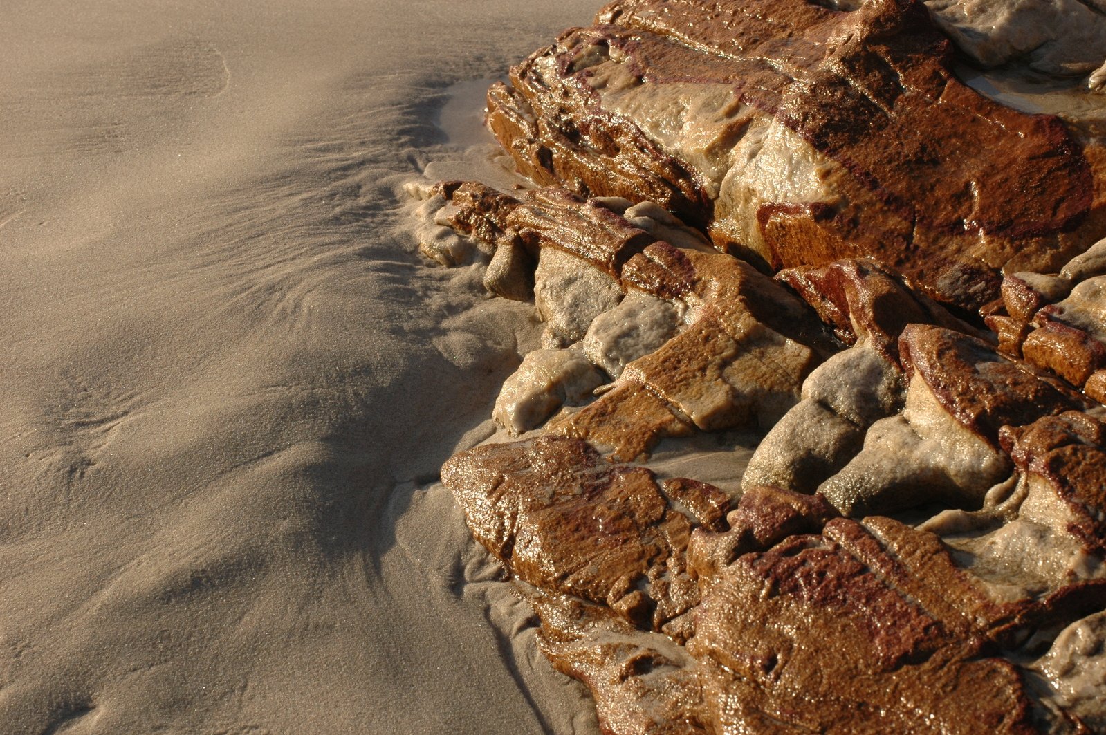 some rocks and dirt at the edge of a sandy beach