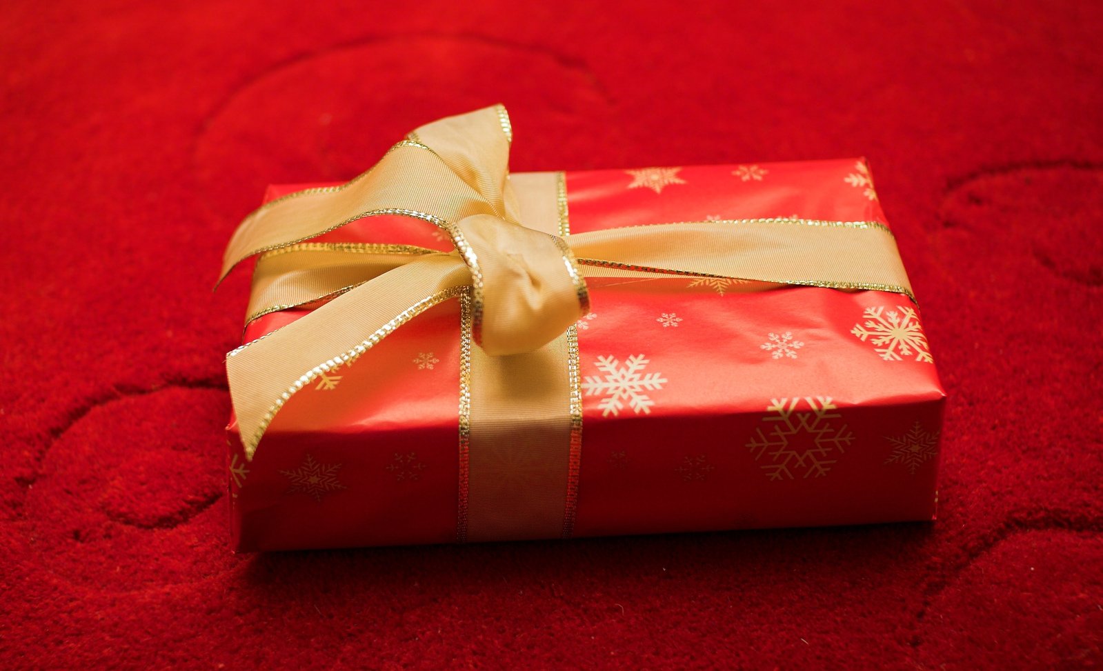 a gift wrapped in paper is on a red table