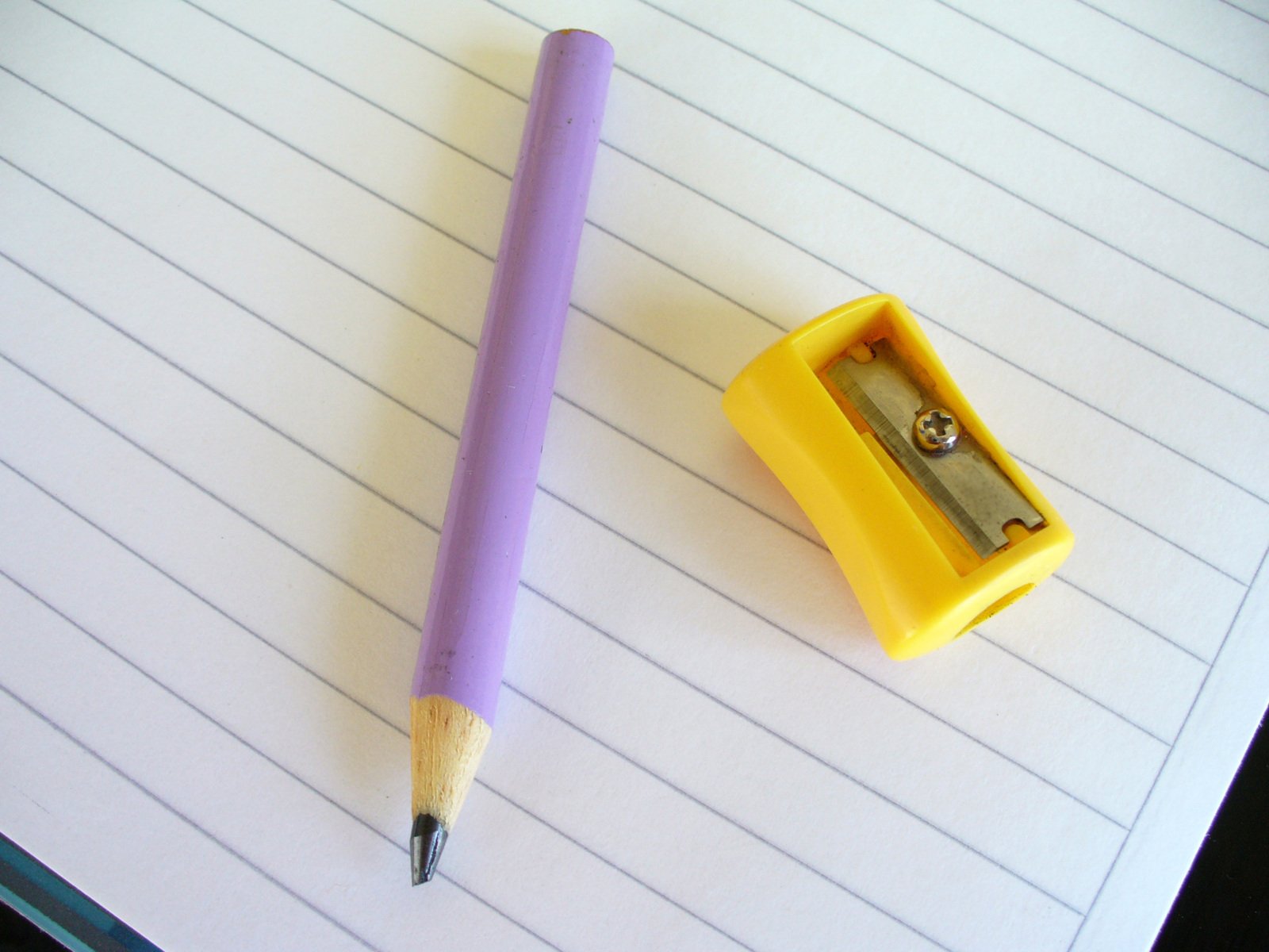 a purple pen is next to a yellow plastic pencil holder
