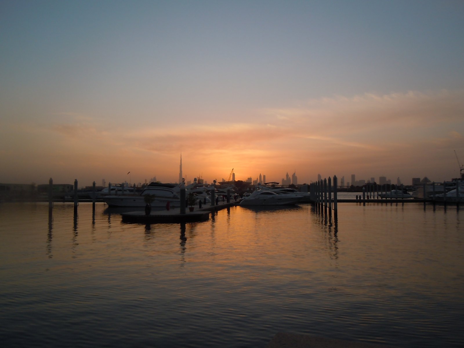 the sun setting over a marina full of boats